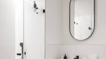 Une salle de bain moderne avec une douche à parois de verre, un meuble-lavabo noir, un grand miroir et un porte-serviettes.