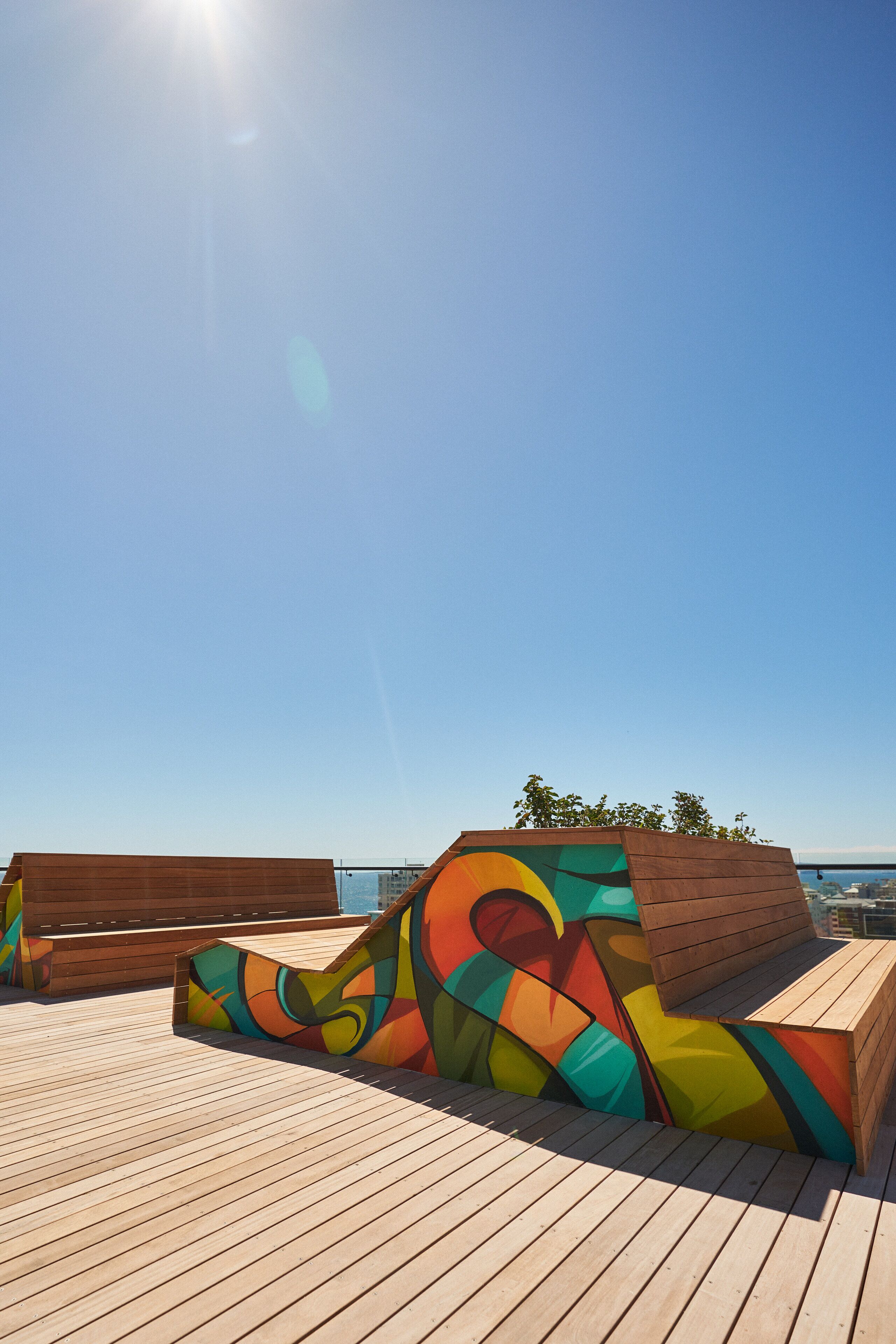 A wooden deck with colorful abstract art and a view of the sea.