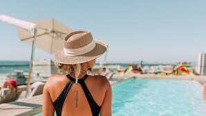 A person sitting by a pool with a clear view of the sea and other poolside amenities. - Home Suite Hotels Station House (Cape Town)