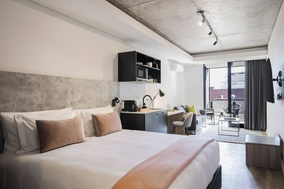Habitación de hotel moderna con una cama grande, un escritorio y vistas a la ciudad.