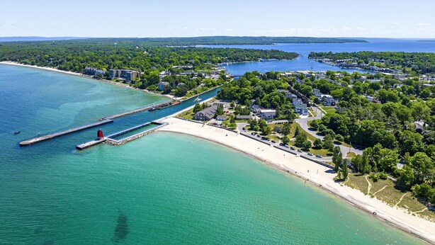Luftaufnahme einer Küstenstadt mit einem Yachthafen, Sandstränden und Wohngebieten.