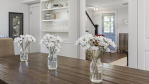 Ein Esstisch mit drei Glaskolben, gefüllt mit weißen Blumen.