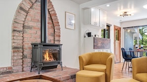 Un salon chaleureux avec une cheminée en briques, des meubles modernes et une vue sur l’extérieur.