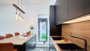 A modern kitchen with a wooden countertop, a black sink, and a dining area with chairs. - Hedera Estate, Hedera A15 (Dubrovnik)