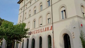 A multi-story building with arched windows and a sign reading "REVERSIANA". - RE-Versiliana (Pietrasanta)