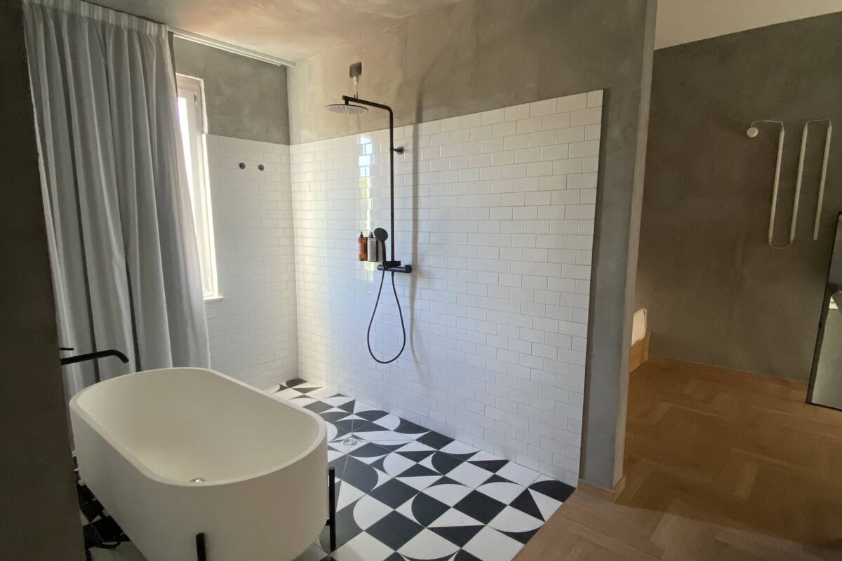 A modern bathroom with a freestanding bathtub, a shower with a rain showerhead, and a patterned floor.