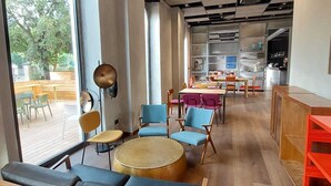 A modern interior with seating areas, large windows, and a kitchen in the background. - RE-Versiliana (Pietrasanta)