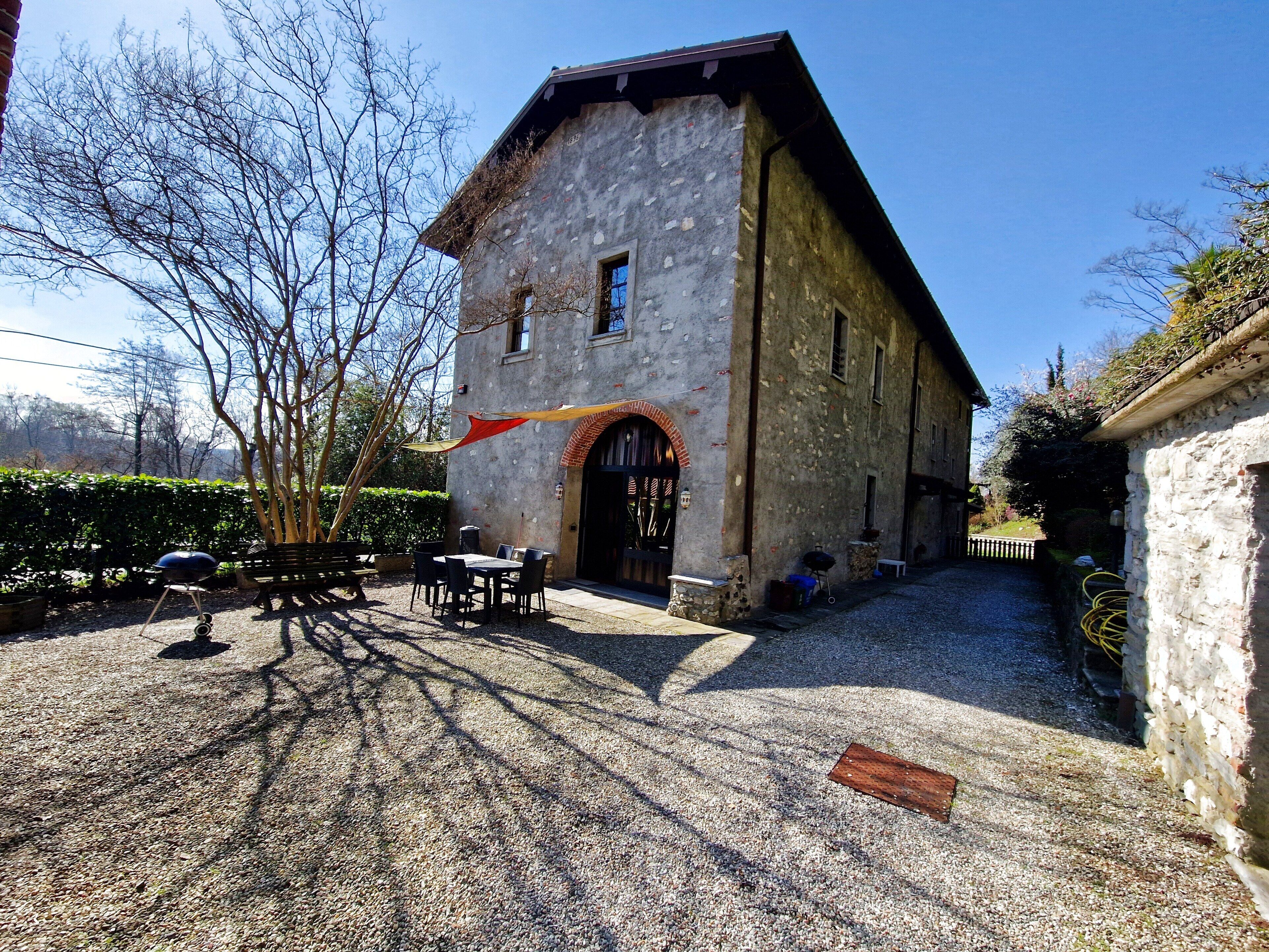 A stone building with a gravel courtyard, outdoor seating, and a flag.