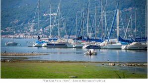 A marina with multiple sailboats docked, a grassy foreground, and a hillside town in the background. - The Gulf Sailor's Cottage - Lake Maggiore (Cantone)