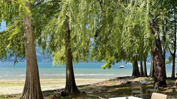 An outdoor seating area with a table and chairs, overlooking a body of water with boats. - The Gulf Sailor's Cottage - Lake Maggiore (Cantone)