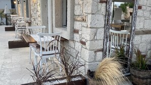 A stone building with outdoor seating, a large ornate mirror, and decorative plants. - Serez Otel Alaçatı by La Mira (Cesme)