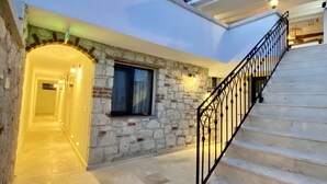 A building with a stone facade, a staircase, and a well-lit interior corridor. - Serez Otel Alaçatı by La Mira (Cesme)