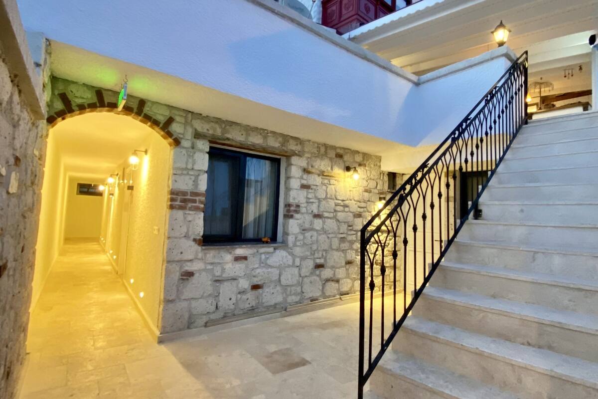A building with a stone facade, a staircase, and a well-lit interior corridor.