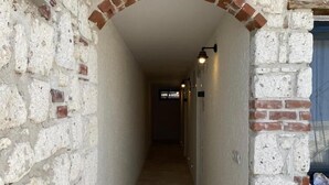 A narrow corridor with a brick archway, tiled floor, and wall-mounted light fixtures. - Serez Otel Alaçatı by La Mira (Cesme)