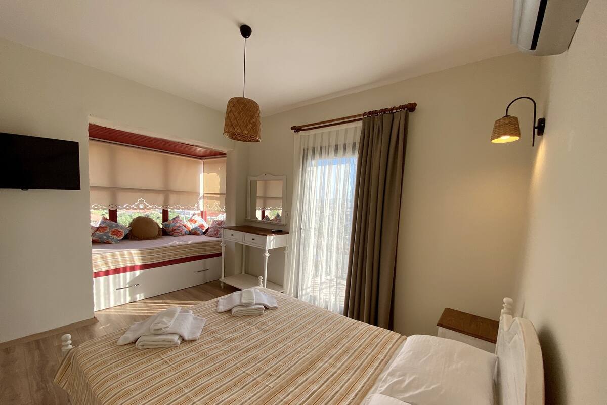 A bedroom with a bed, bedside table, and a view of a balcony.