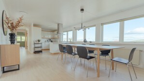 A modern kitchen with a large island, white cabinetry, and a view of the outdoors through large windows. - Large Penthouse Apt - Downtown - Marina (Tórshavn)