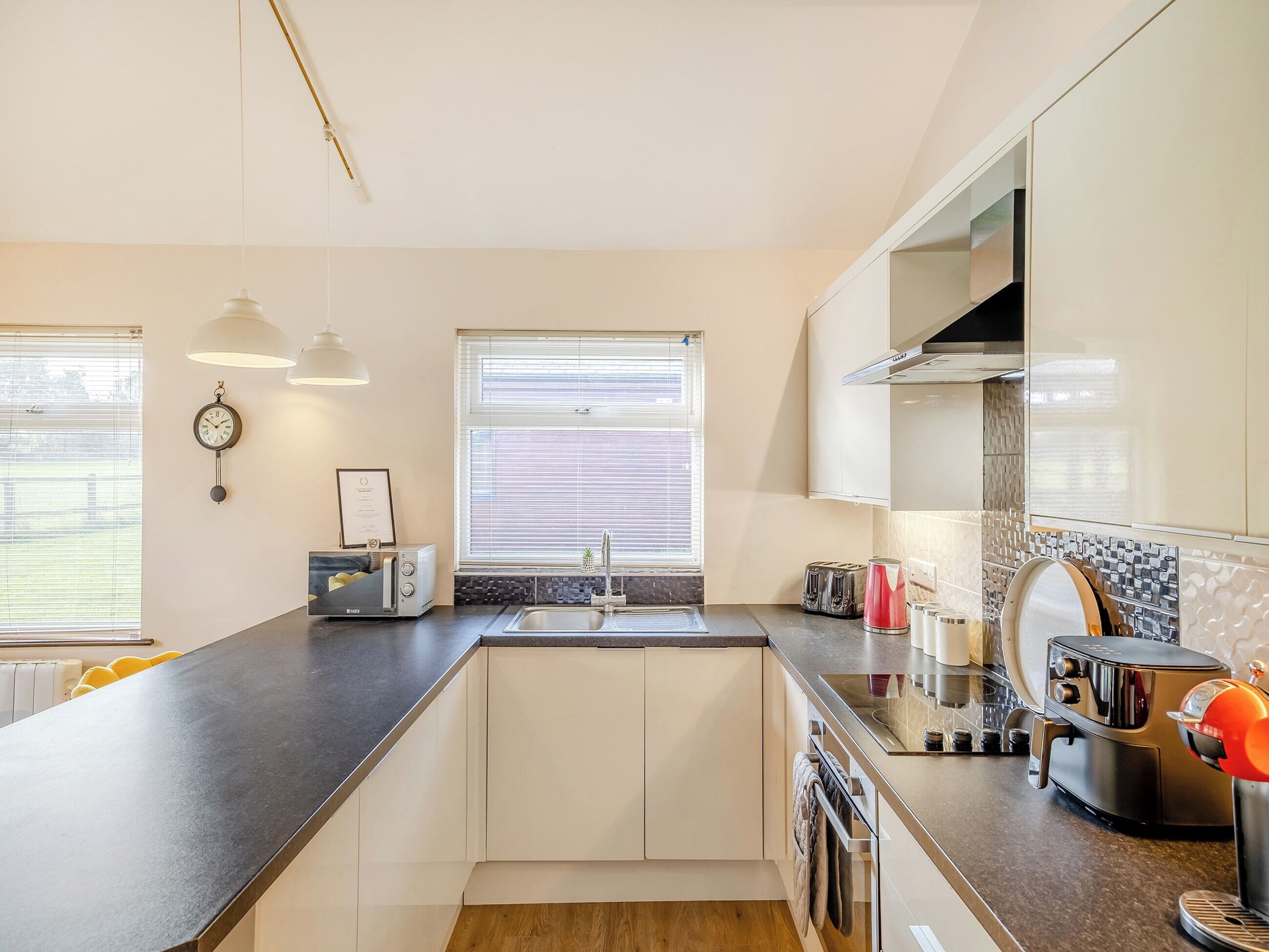 A modern kitchen with a central island, built-in appliances, and a large window providing natural light.