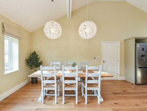 A dining area with a wooden table, white chairs, and two hanging light fixtures.