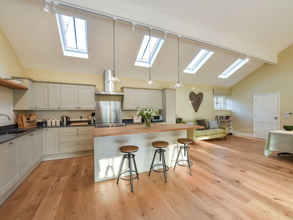 A spacious kitchen with a central island, bar stools, and a heart-shaped wall decoration.