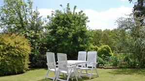 A white outdoor table and chairs set in a grassy area with dense greenery and trees in the background. - 2 bedroom accommodation in Lanreath, near Looe (Lanreath, near Looe)