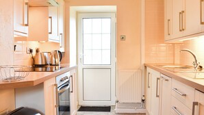 A modern kitchen with white cabinets, stainless steel appliances, and a black countertop. - 2 bedroom accommodation in Lanreath, near Looe (Lanreath, near Looe)