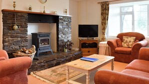 A cozy living room with a stone fireplace, a television, and comfortable seating. - 2 bedroom accommodation in Lanreath, near Looe (Lanreath, near Looe)