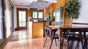 A spacious kitchen with wooden cabinets, a central island, and a dining area with chairs.