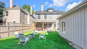A backyard with a wooden deck, a covered patio, and a fenced area.