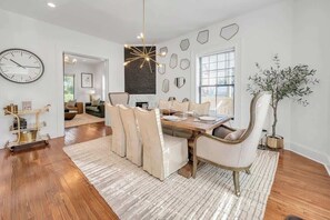A dining area with a wooden table, white chairs, and a chandelier.
