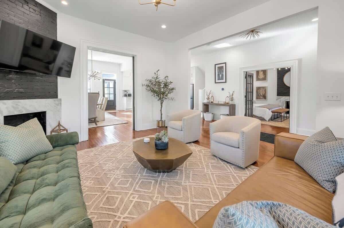 Una sala de estar moderna con chimenea, un televisor grande y un comedor con mesa y sillas.