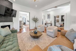 Una sala de estar moderna con chimenea, un televisor grande y un comedor con mesa y sillas.