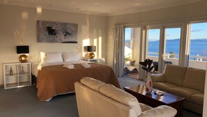 Una habitación de hotel con una cama, un sofá, una mesa de centro y vistas al mar.