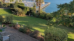 Een jachthaven met boten, een steiger en een gazon met bomen en struiken.