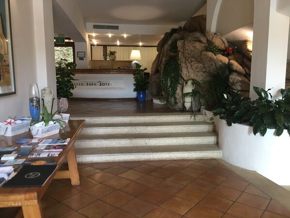 Ein Empfangsbereich mit Steinwand, einer Rezeption und einer Treppe zum Obergeschoss.