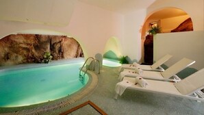 A spa area with a pool, lounge chairs, and a rock wall. - Vacations on the Emerald Coast in Cala di Volpe (loc. cala di volpe)