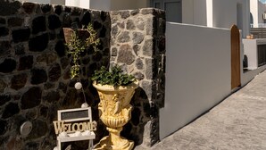 Un moderno edificio blanco con un muro de piedra, un cartel de bienvenida y una planta en maceta.