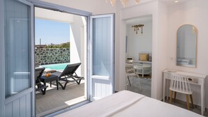 Un dormitorio con una cama grande, un escritorio, una silla y vista a una piscina al aire libre.