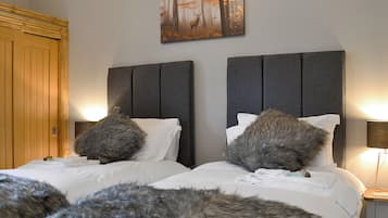 A bedroom with two beds, a wooden wardrobe, and a painting on the wall.