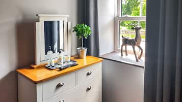 A bathroom with a vanity, a mirror, a potted plant, and a window with a deer statue.