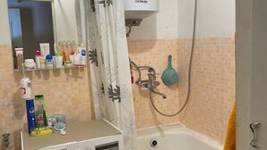 A bathroom with a washing machine, a bathtub, a shower, and a toilet.