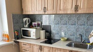 A kitchen with wooden cabinets, a microwave, a coffee maker, and a sink.