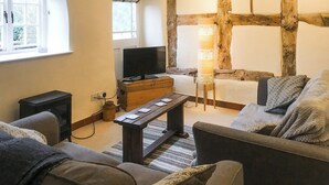 A cozy living room with a television, a wooden chest, a standing lamp, and a sofa. - Jasmine Cottage - UK4176 (Middle Mayfield, near Ashbourne)