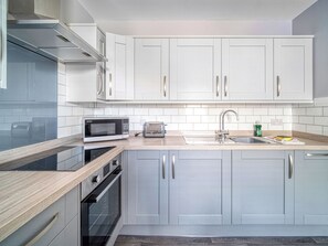 Una cocina moderna con armarios blancos, microondas, tostadora y pileta.