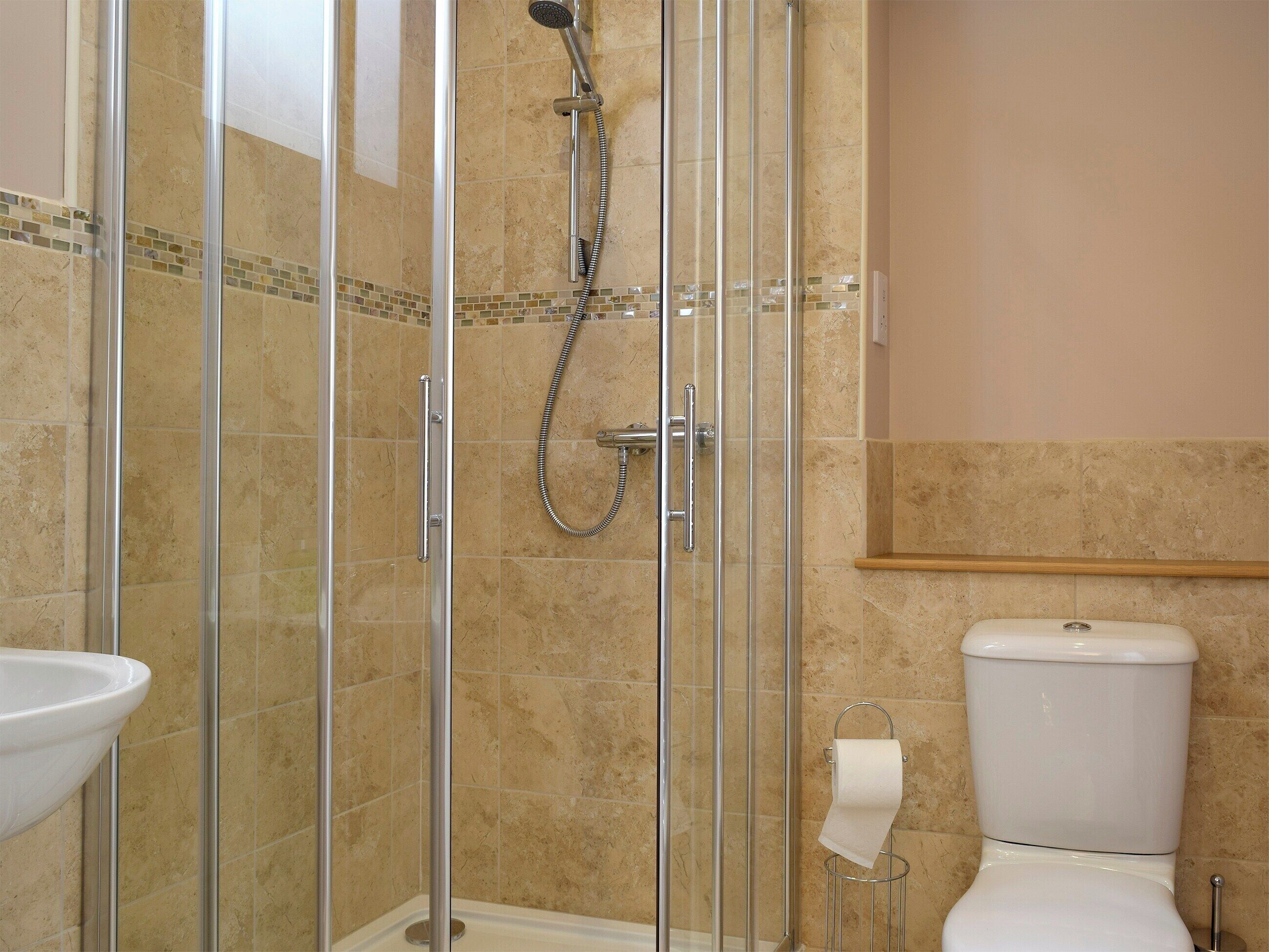 A bathroom with a glass-enclosed shower, a toilet, and a sink.