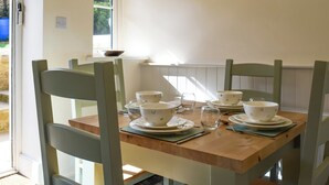 Una mesa de comedor dispuesta con fuentes y platos blancos, rodeada de sillas verdes.