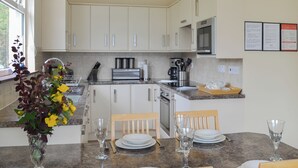 A modern kitchen with white cabinets, stainless steel appliances, and a dining area with a table set for two. - 2 bedroom accommodation in by Inverinate, Kyle (by Inverinate, Kyle)