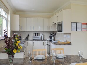 A modern kitchen with white cabinets, stainless steel appliances, and a dining area with a table set for two.
