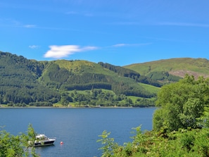 A lake surrounded by green hills and a boat anchored near the shore.