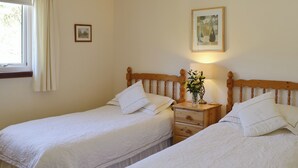 A bedroom with two single beds, a nightstand with a lamp, a framed picture on the wall, and a window with curtains. - 2 bedroom accommodation in by Inverinate, Kyle (by Inverinate, Kyle)