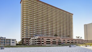 A tall, multi-story hotel with numerous balconies and a parking structure.